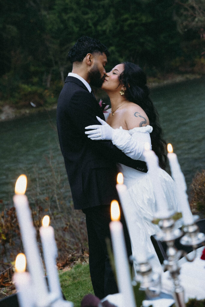 A couple shares a kiss in front of a table scape on a river in the cascade mountains for their cascade mountain elopement