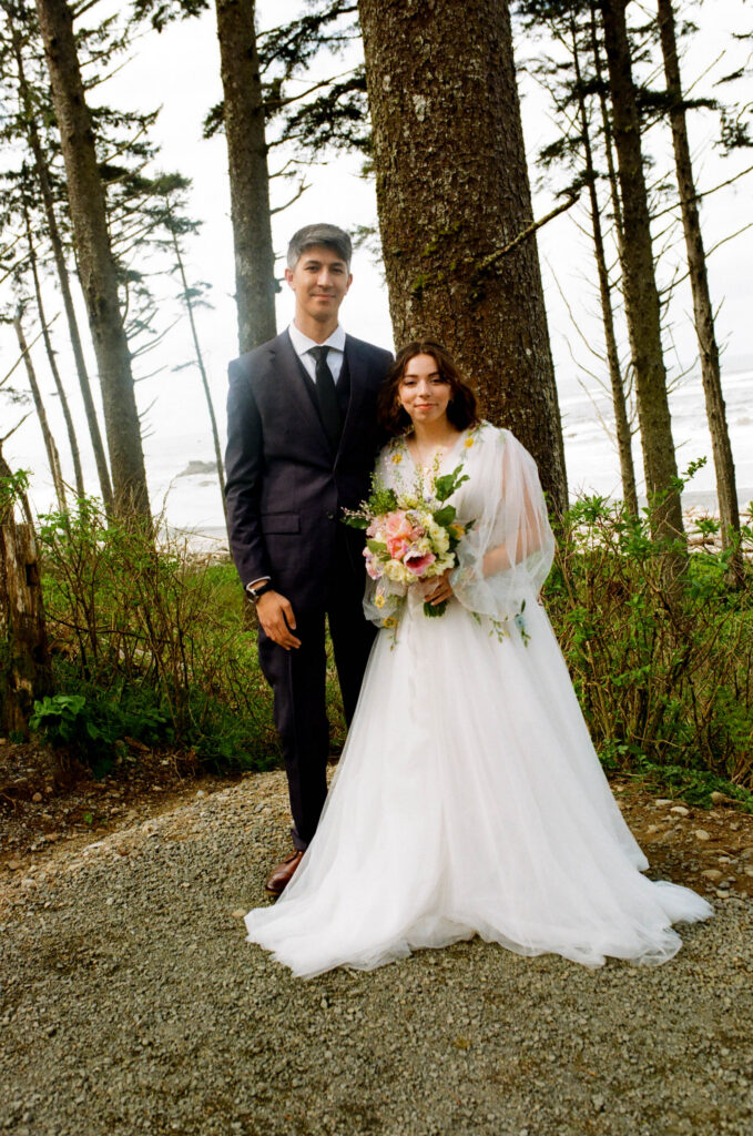 couple in elopement attire standing among coastal trees at Ruby Beach Washington Olympic Peninsula
