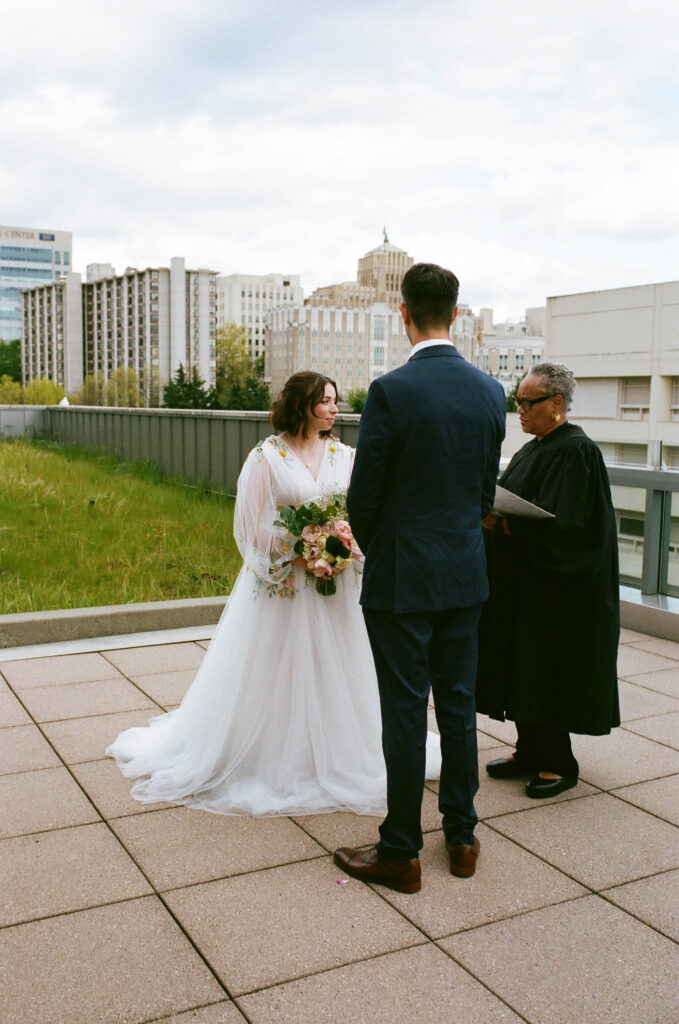 couple exchanging vows on rooftop with Seattle skyline during city elopement ceremony with officiant Washington State